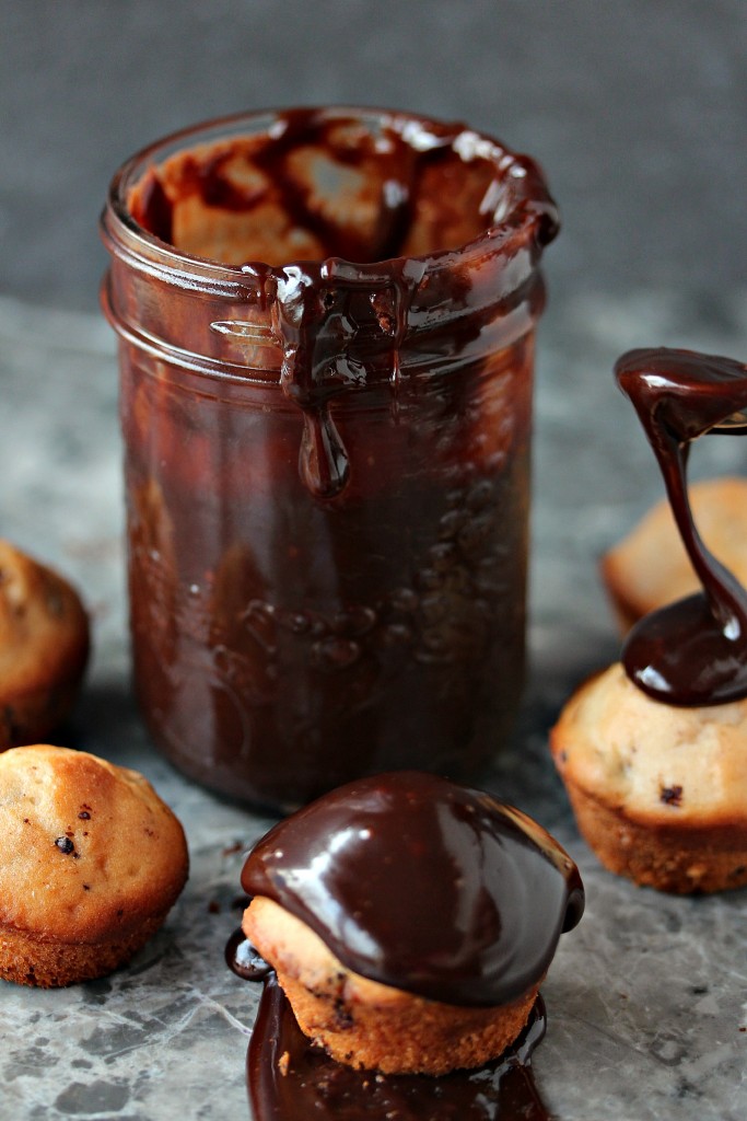 Nutella Ganache in a mason jar with a spoon in it and muffins all around it 