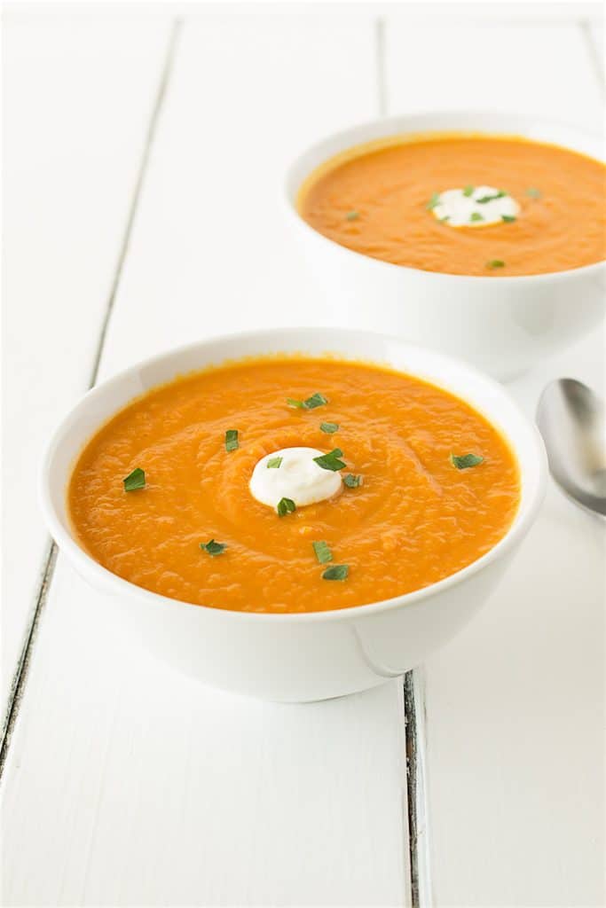 Carrot soup served in white bowls. 
