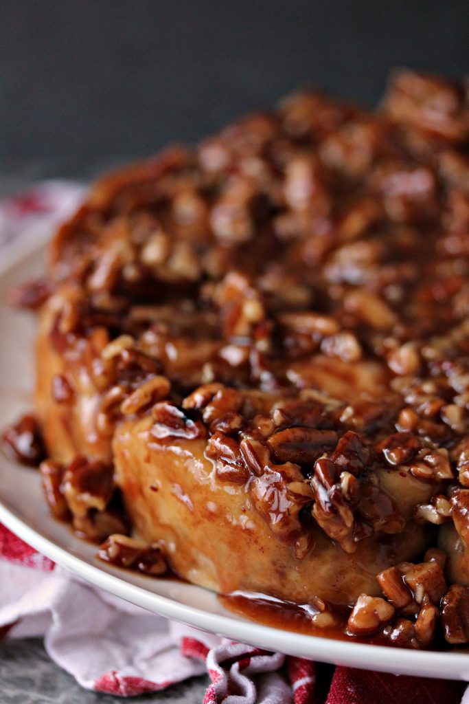 Overnight Apple Pecan Caramel Sticky Buns served on a white plate on a red and white napkin.