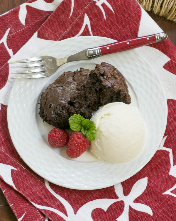 Slow Cooker Brownie Dessert – That Skinny Chick Can Bake image of finished recipe on a white plate with vanilla ice cream and fresh raspberries on it. 