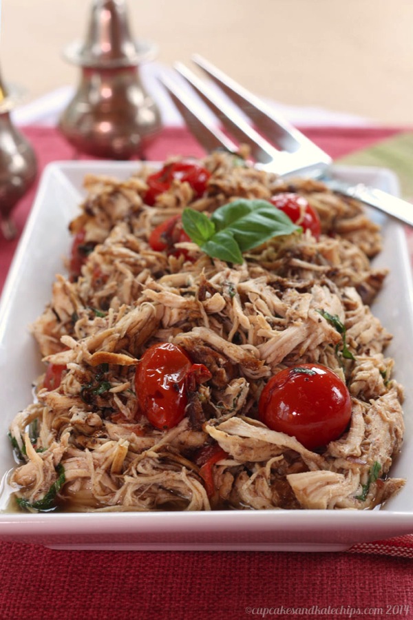 Slow Cooker Tomato Basil Pulled Chicken – Cupcakes & Kale Chips image of finished recipe on a white platter with a fork resting in the top corner. 