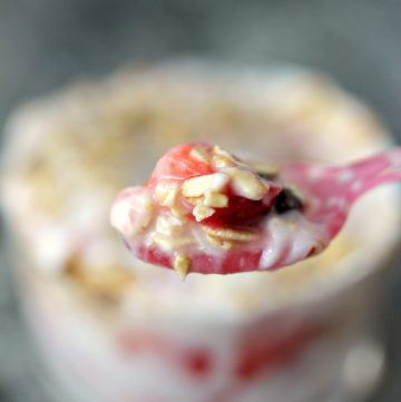 Strawberry Yogurt Parfaits close up image on spoon with glass in the background