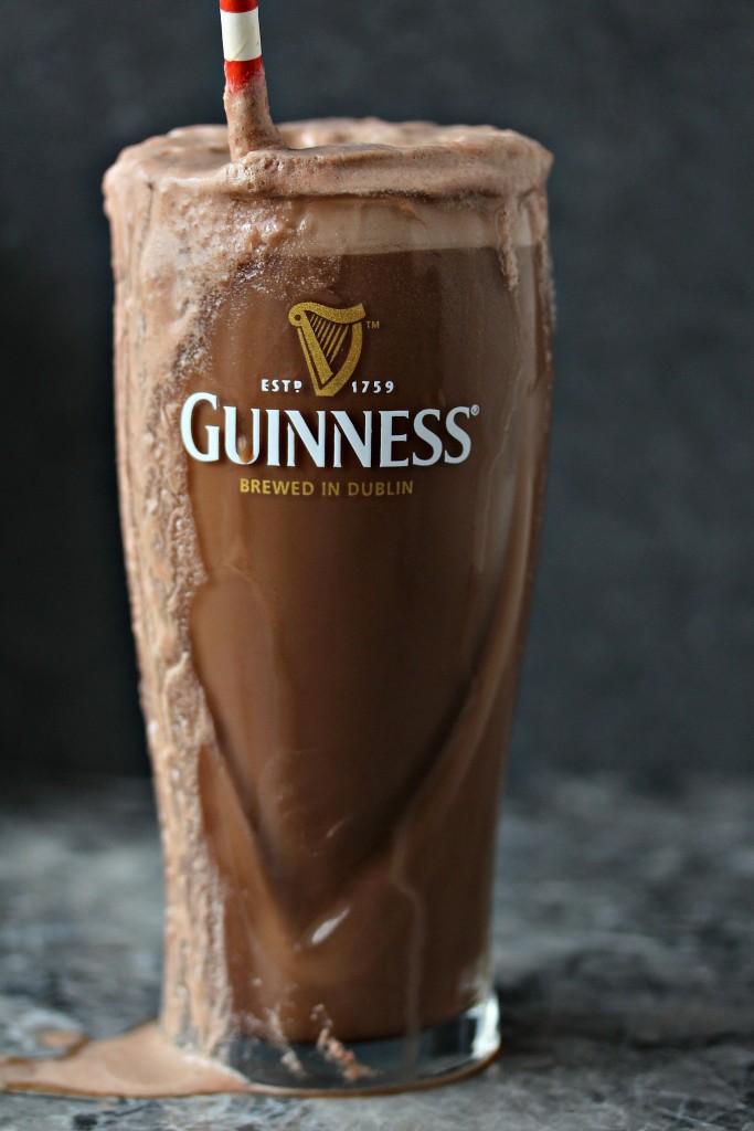 Chocolate Guinness float in a tall glass with a straw, and drink dripping down the side of the glass.