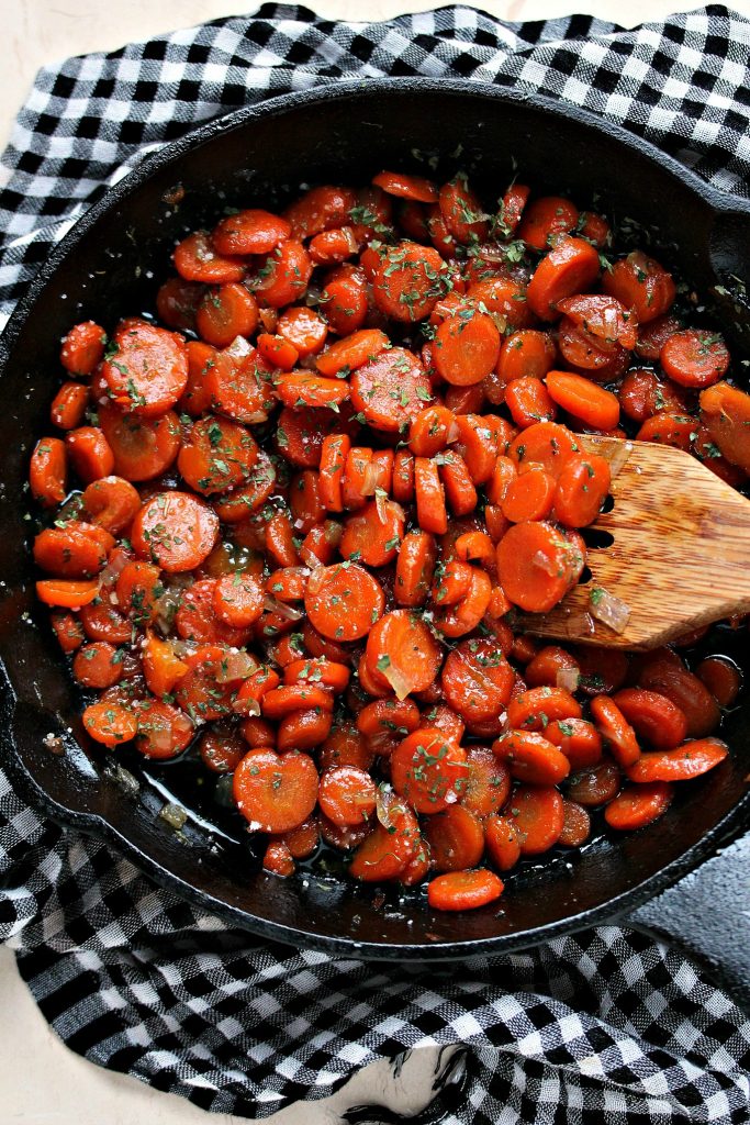 Honey Glazed Carrots in a black cast iron pan resting on a black and white checkered napkin.