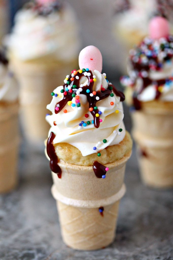 Mini ice cream cone cupcakes topped with hot fudge sauce, sprinkles and jelly beans