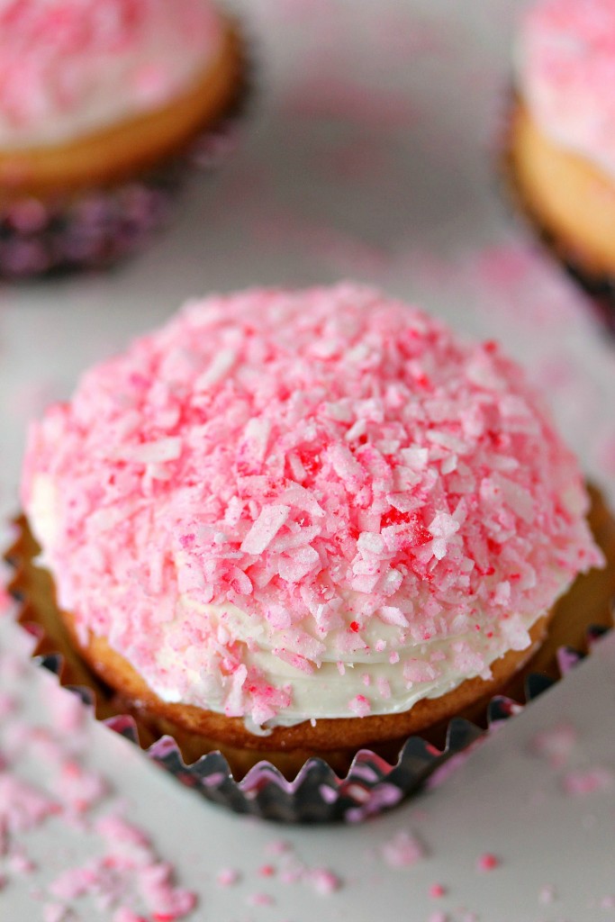 cupcakes on a counter with pink coconut on top of the frosting