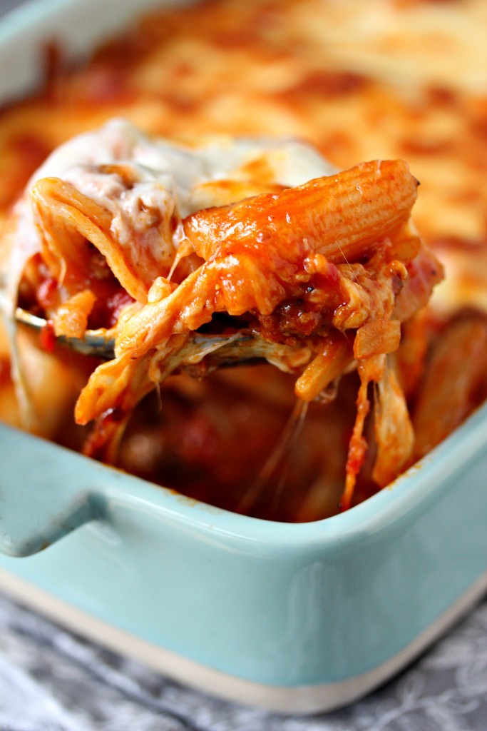 Easy Cheesy Pasta Bake with Sausage and Peppers in a blue casserole dish with a spoonful being taken out.
