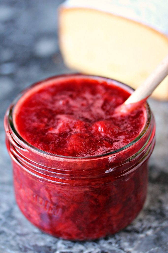 Strawberry Compote in a mason jar with a wooden spoon. 