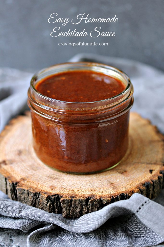 Easy Homemade Enchilada Sauce in a mason jar on a wood board sitting on a grey napkin. 
