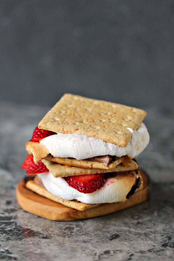 Grilled Strawberry and Caramel S'mores served on a wooden coaster.
