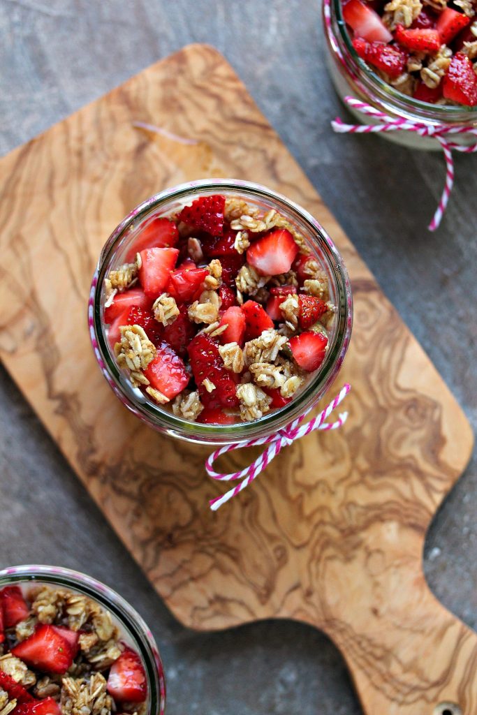 Strawberry and Banana Yogurt Parfaits overhead image of mason jars on a wood serving board.