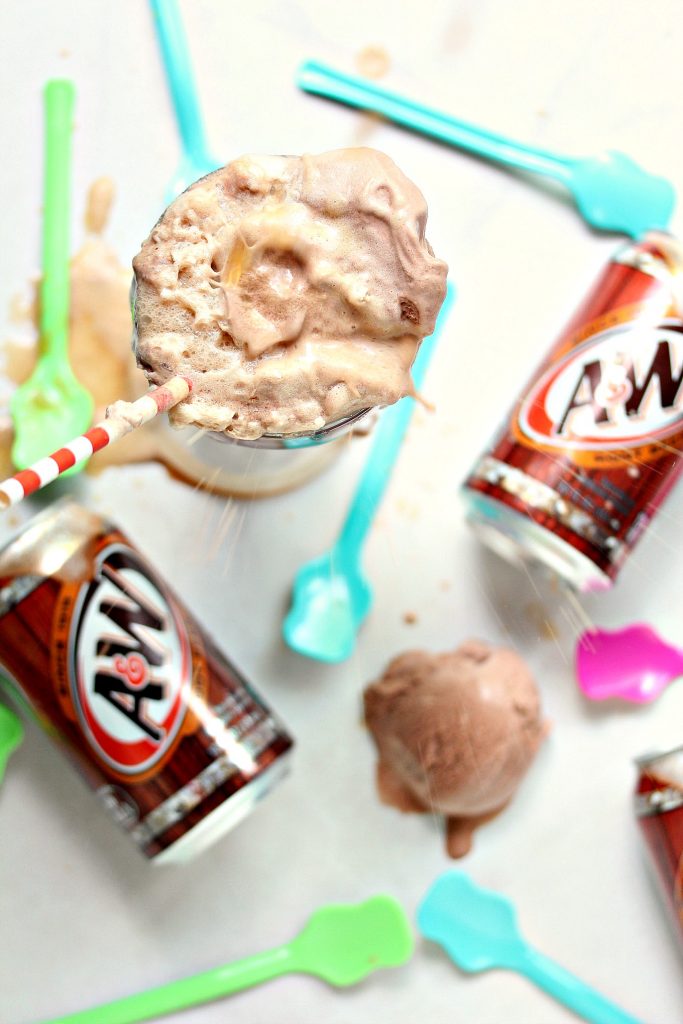 overhead image of Chocolate Hot Fudge Root Beer Float on a white surface with cans of root beer, spoons and floats seen