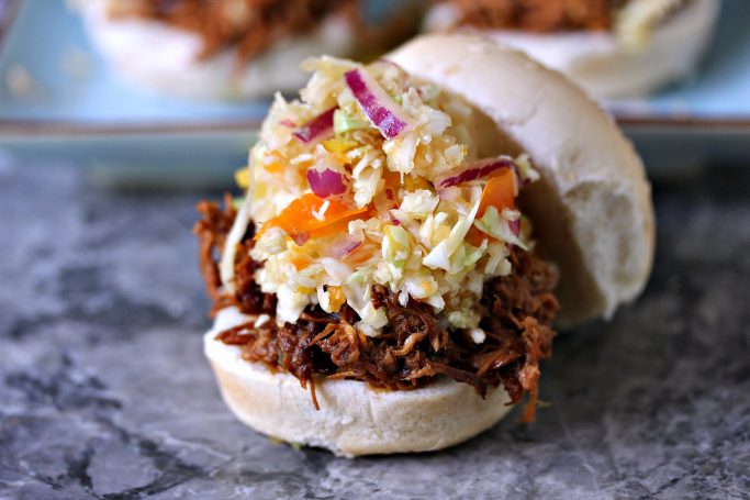 Slow Cooker Pulled BBQ Chicken Sandwich with slaw on top of it.