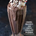 Caramel Macchiato Iced Coffee Chocolate Milkshakes in a milkshake glass with whipped cream, chocolate sauce and a cherry on top. A striped straw is inside the drink and there is a drip of chocolate shake on the front of the glass. Text is in the lower right corner that states the recipe and blog name.