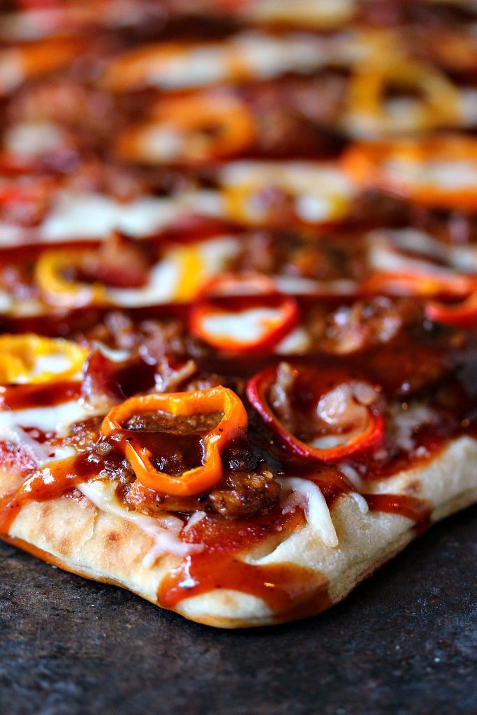grilled flatbread pizza topped with shredded chicken, baby peppers and bacon