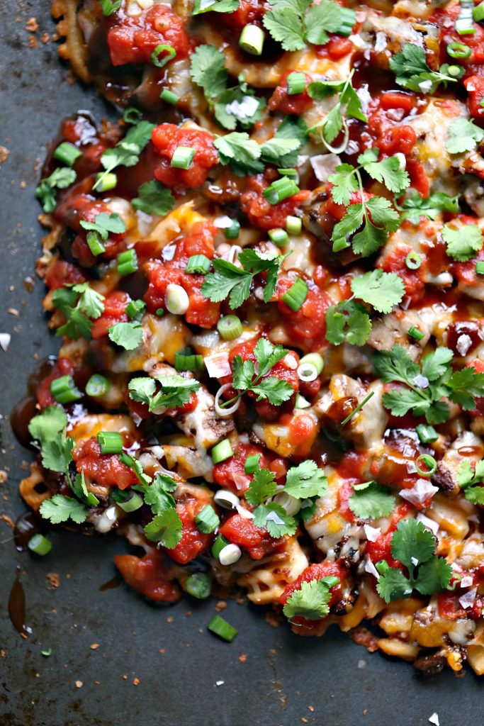 Sheet Pan Steak and Waffle Fry Nachos from cravingsofalunatic.com- These loaded nachos are made with waffle fries, steak and Tex-Mex cheese then topped with barbecue sauce, salsa, onions, and cilantro. All cooked on a sheet pan to make clean up a snap. 