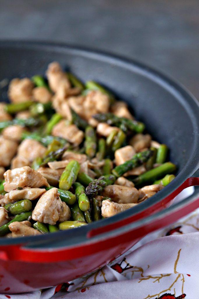 Chicken and asparagus stir fry in a red wok. 