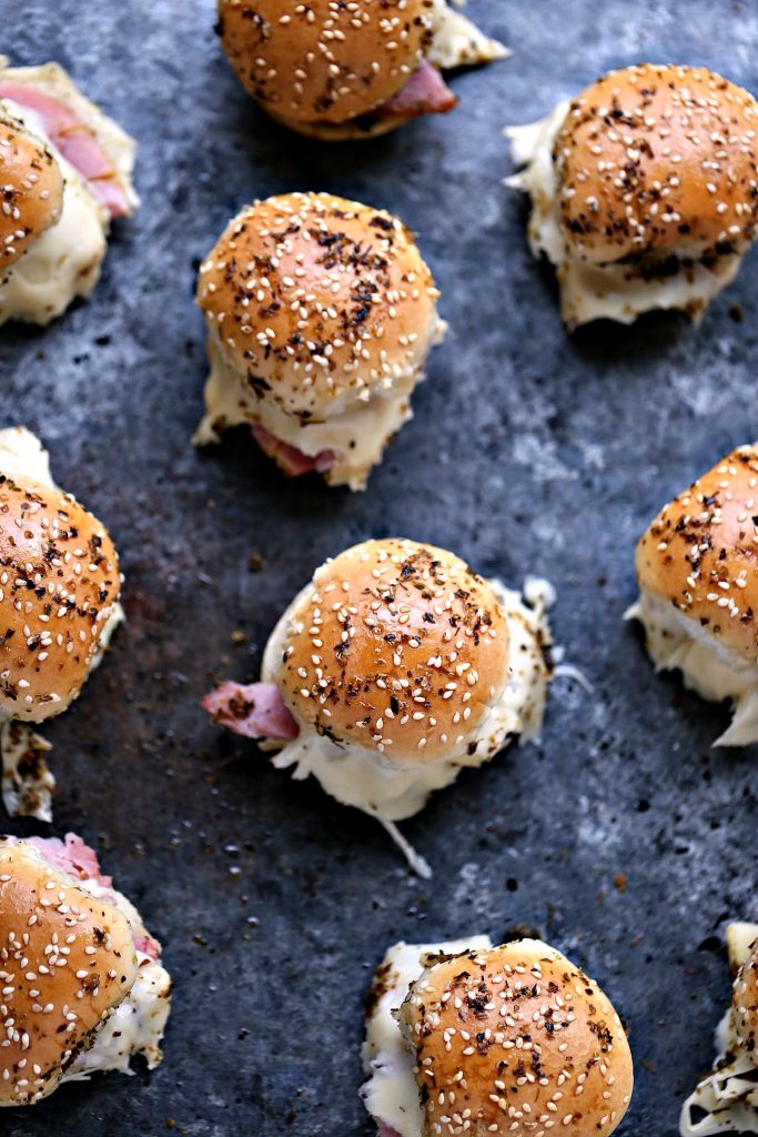 Overhead image of ham and cheese sliders on a dark counter. 
