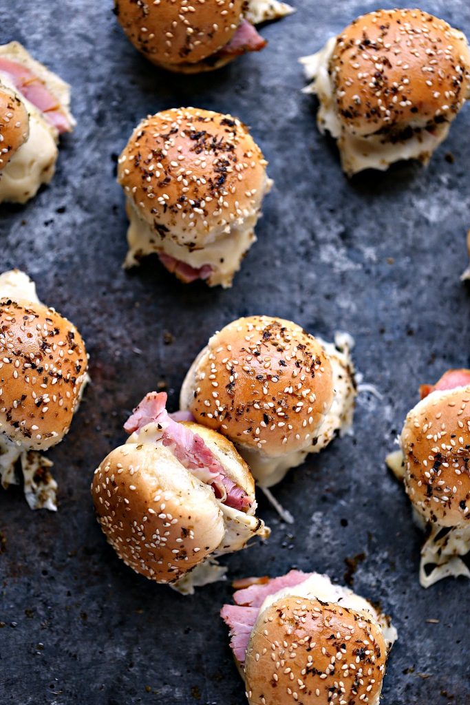 Overhead image of ham and cheese sliders pulled apart and resting on a dark counter.