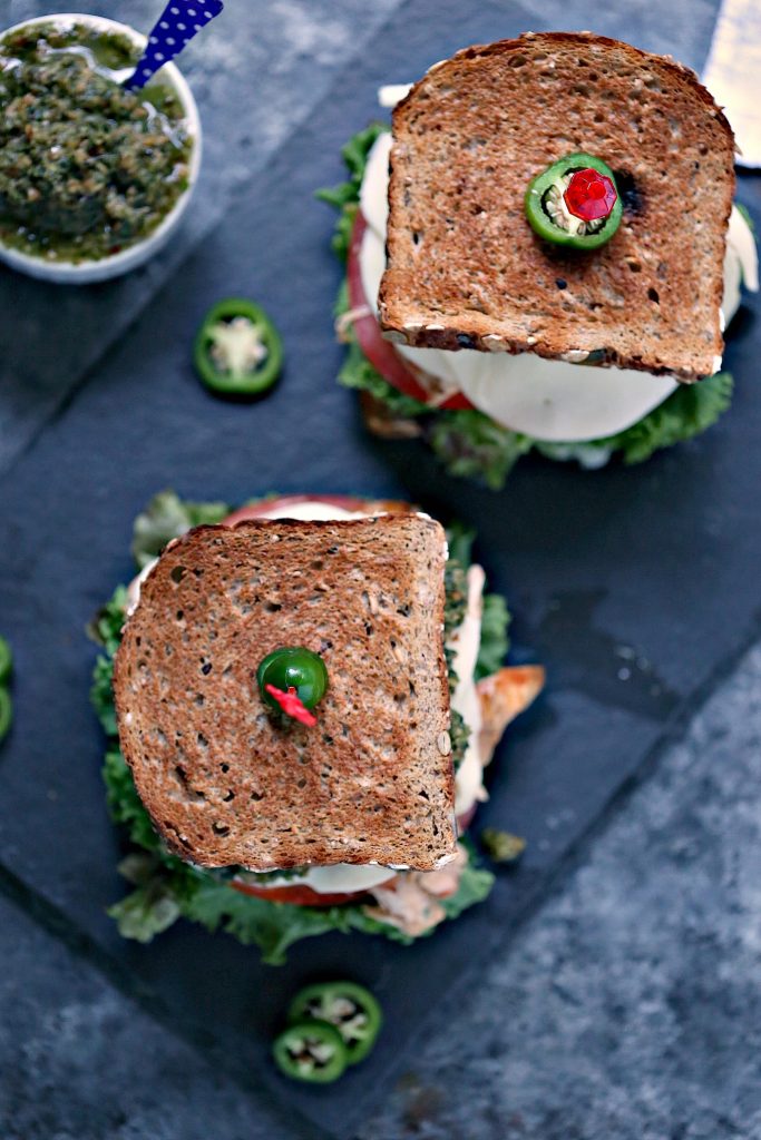 Grilled Chicken Sandwich with Basil Pesto is an easy recipe that will delight your tastebuds. It's piled high with vegetables, chicken, cheese, and pesto.