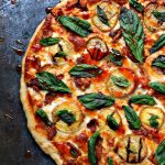 overhead image of a cooked pizza that is topped with grilled peaches, chicken and basil