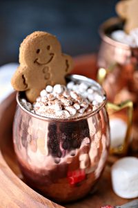 Gingerbread hot chocolate served in mugs with extra mini marshmallows and gingerbread cookies. The perfect cold weather drink!