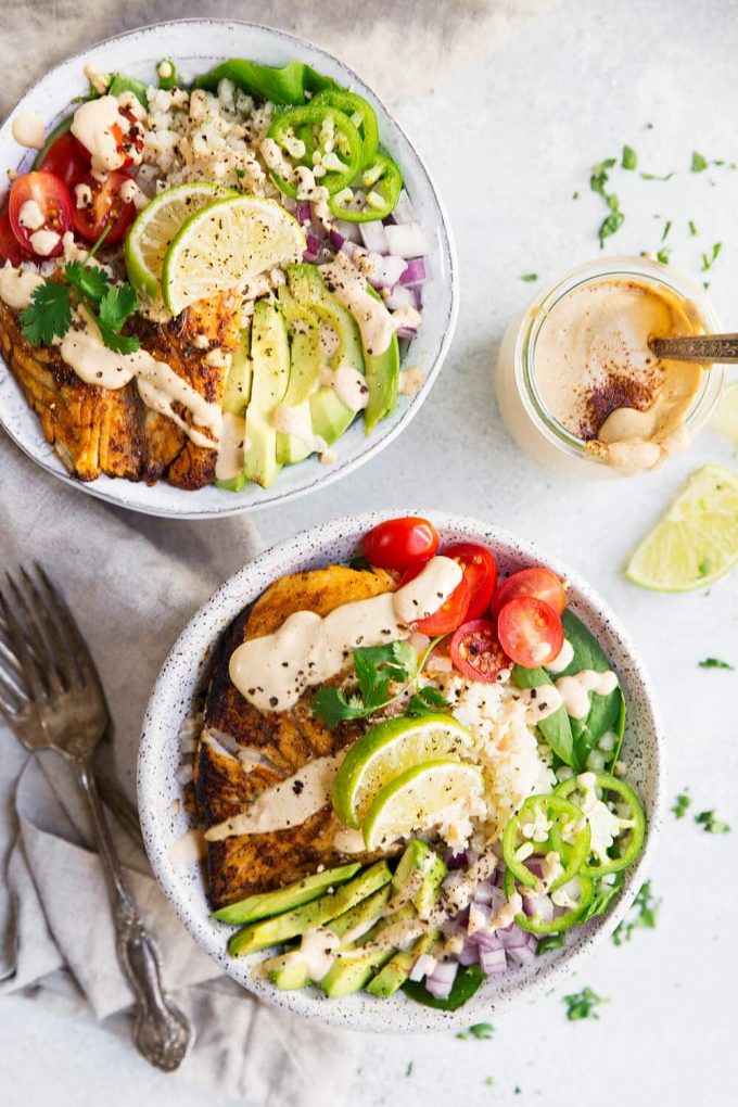 Paleo Fish Taco Bowls from The Movement Menu. These paleo fish taco bowls are such a well balanced meal! They are filled with delicious pan fried barramundi, aka The Sustainable Seabass® fillets, lots of veggies, cauliflower rice, and topped off with a creamy cashew chipotle sauce! 