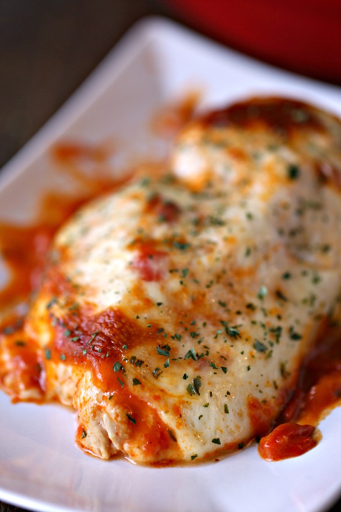 close up image of cooked saucy mozzarella chicken bake on a white plate