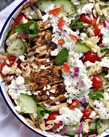overhead image of Greek chicken orzo power bowls on a white napkin