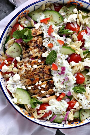 overhead image of Greek chicken orzo power bowls on a white napkin