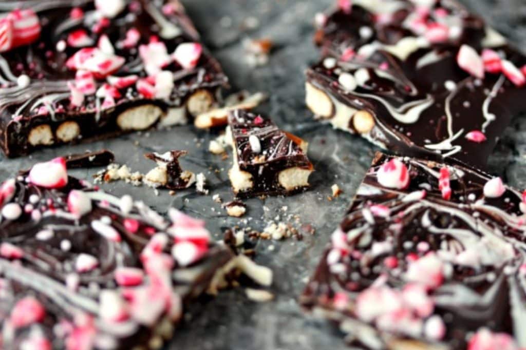 Pieces of pretzel bark with chopped peppermint on top of it cooling on a grey marble counter.