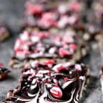 Pieces of pretzel bark topped with chopped peppermint cooling on a grey marble counter.