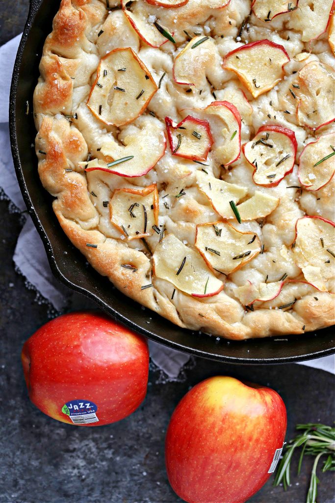 overhead image of focaccia cooked in a black cast iron skillet with Jazz apples nearby