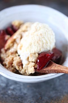 Plum Cobbler served with ice cream in a white bowl.