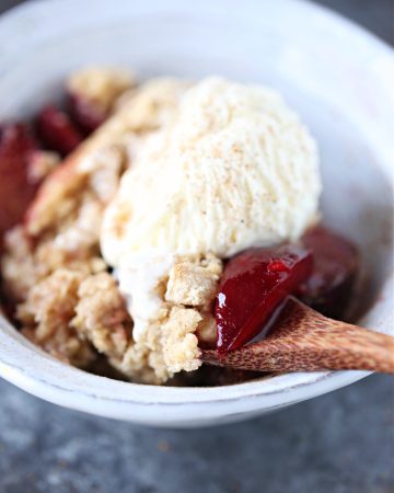 Plum Cobbler served with ice cream in a white bowl.