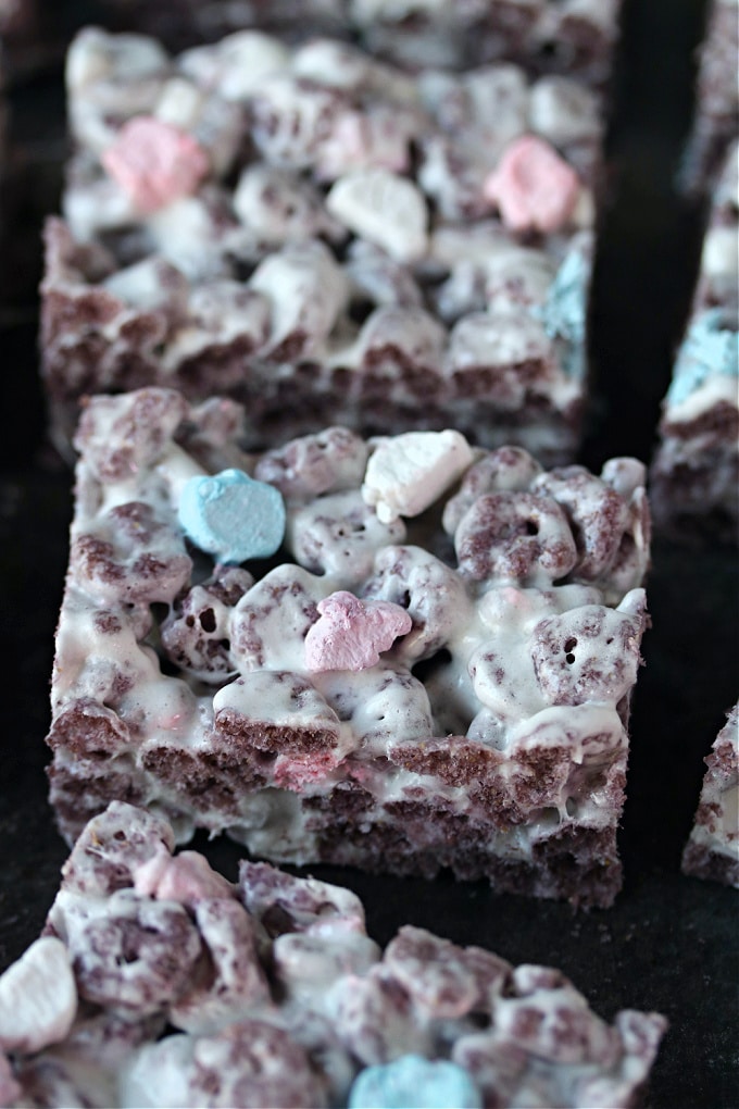 Boo berry krispie treats cut into squares and cooling on dark counter.