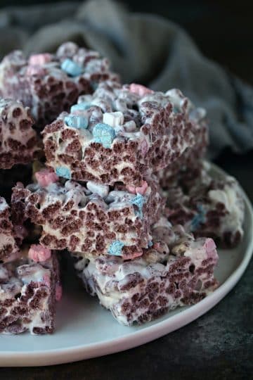 Boo Berry Krispie treats cut into squares and piled on a white plate.