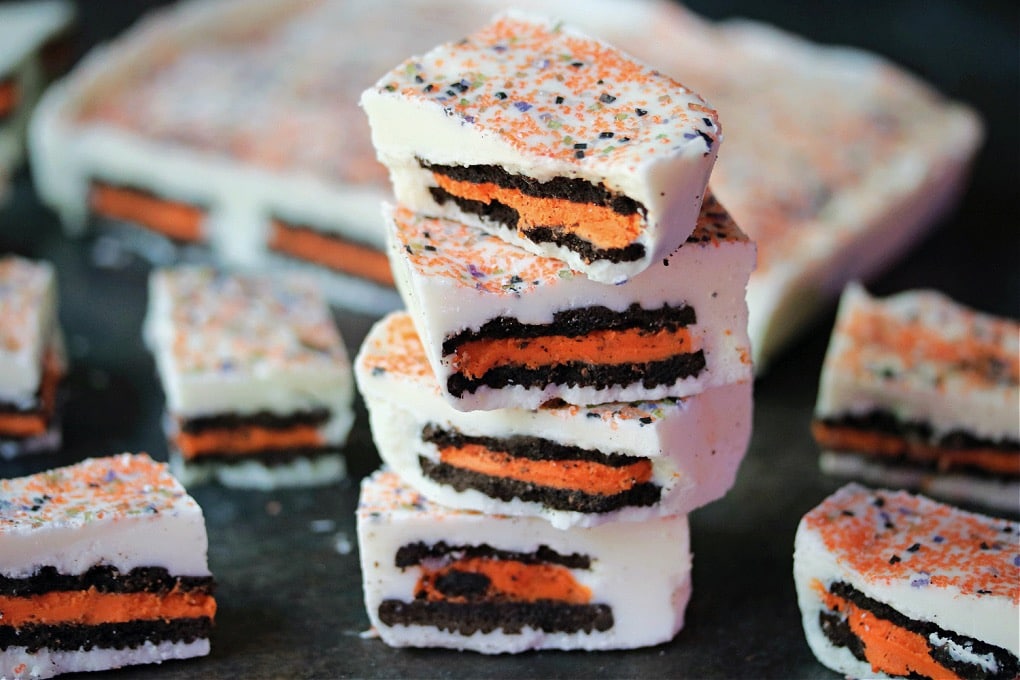 Halloween oreo bark stacked on counter with more candy in the background.