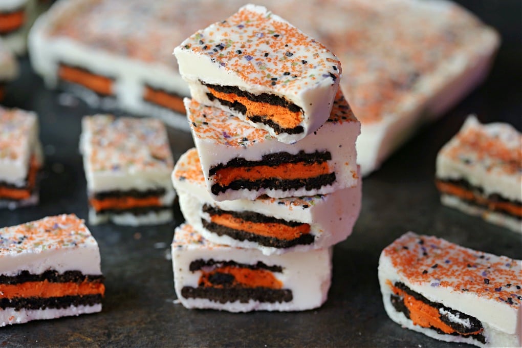 Halloween oreo bark stacked on a dark counter with more bark in the background.