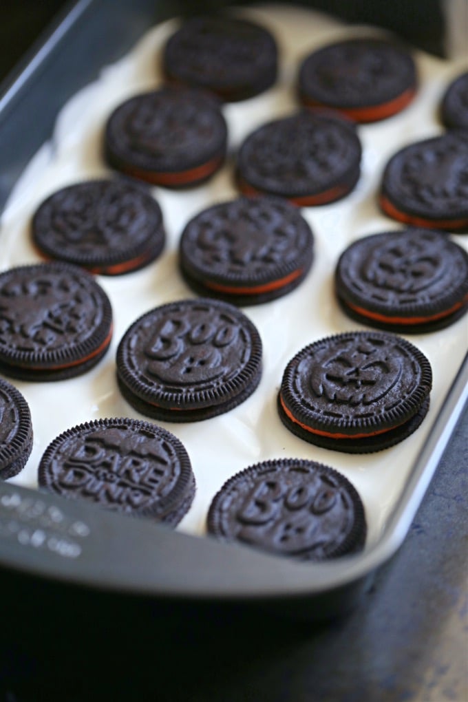 Oreo cookies placed on top of melted almond bark in a baking pan